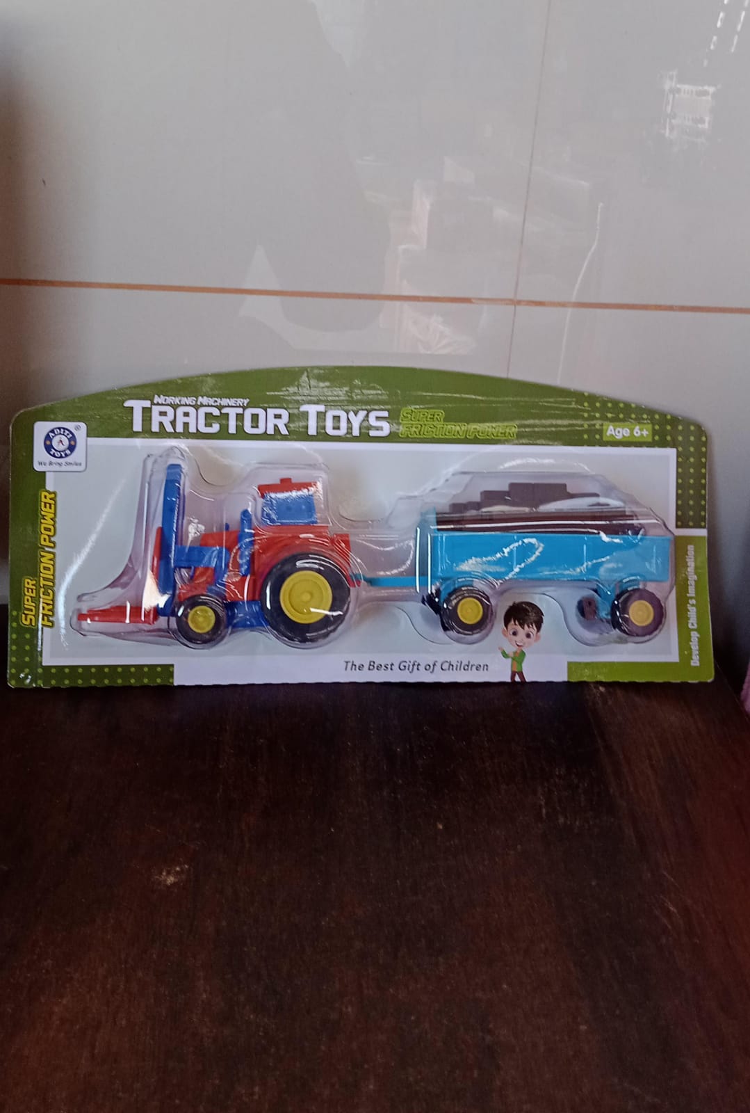 Angled side view of the friction tractor toy with its attached bricks trolley.