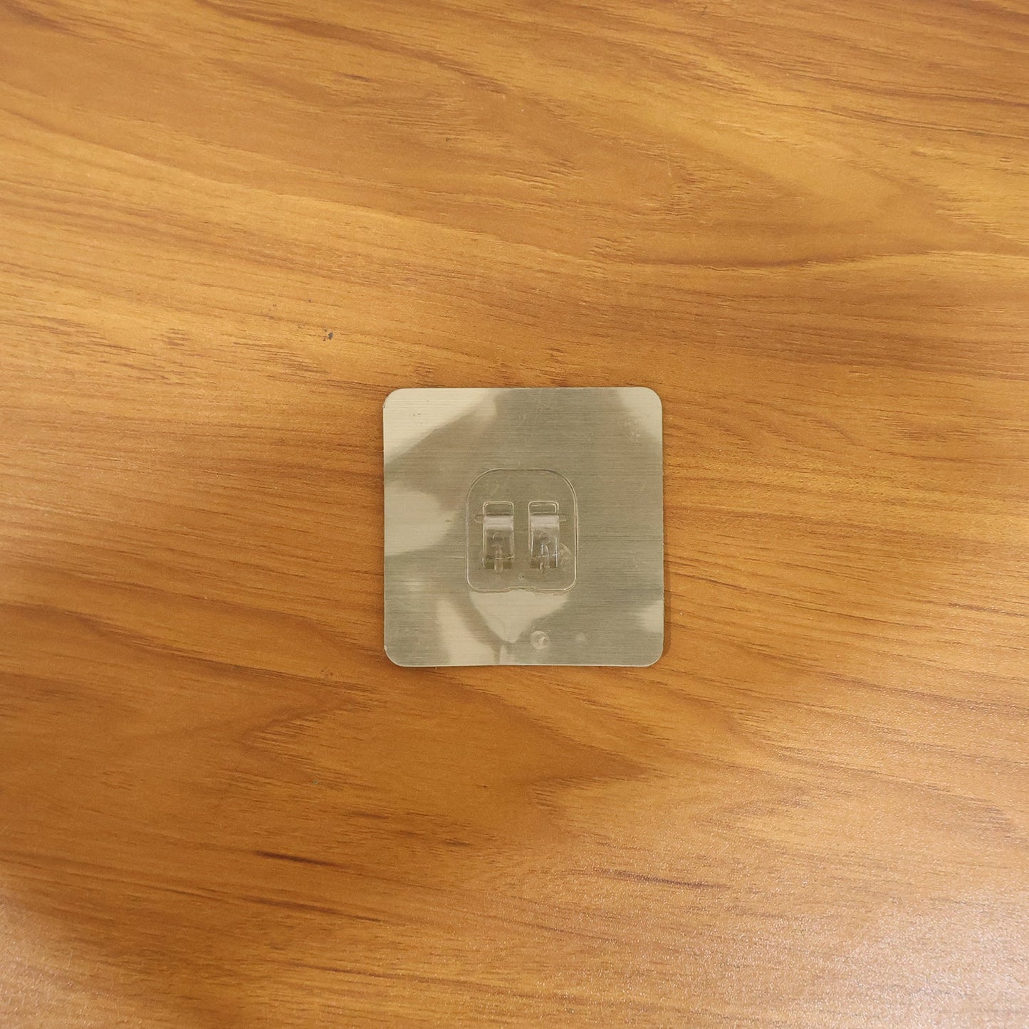 Transparent adhesive wall hook in a real-life home setting, holding various items.