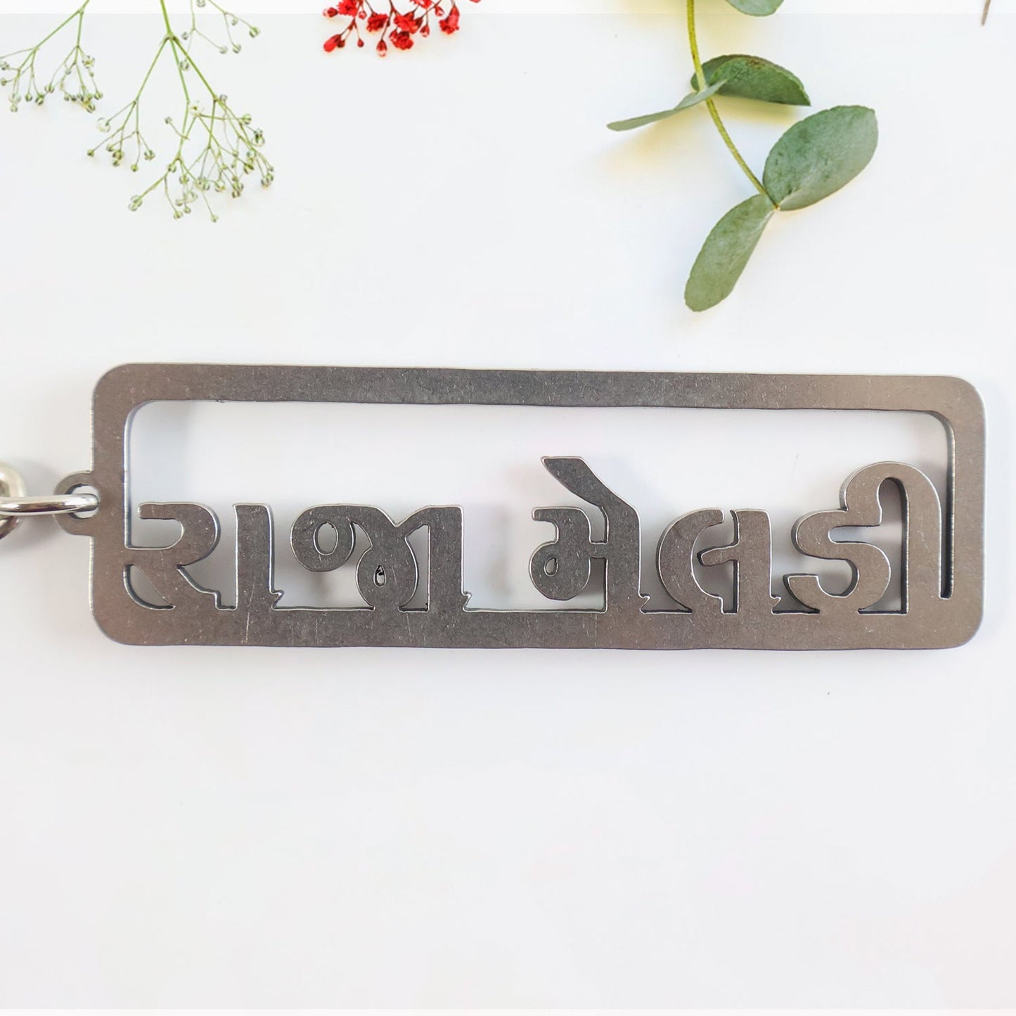 Gujarati text metal keychain featuring devotional design