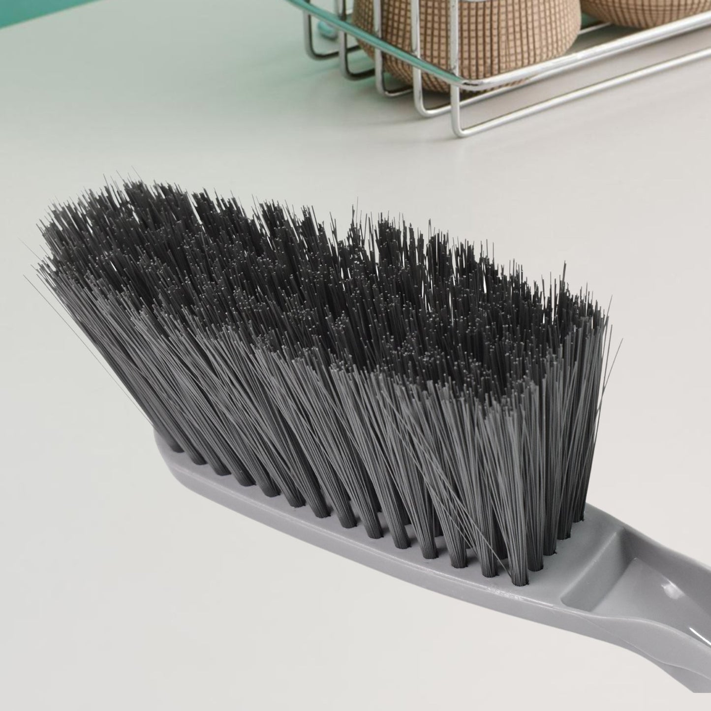 Woman using the long-handle cleaning brush for scrubbing a kitchen sink.