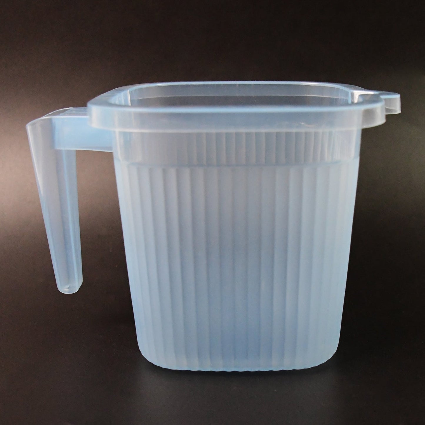 Close-up of the Transparent Bath Mug's sturdy handle and square shape.