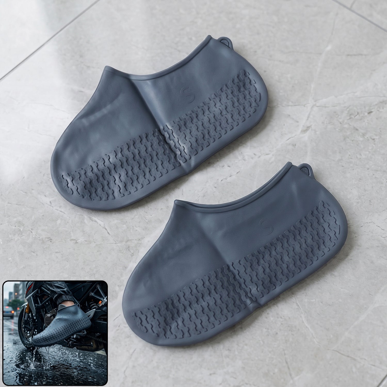 A pair of dark gray silicone shoe covers with textured soles rests on a light gray tiled floor, with an inset of a person